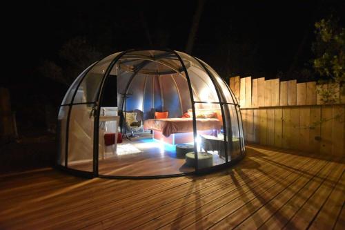 a tent with a bed in it on a deck at Logements insolites du Domaine de la Tuilière in Carnoules