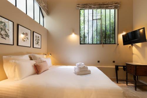 une chambre avec un grand lit blanc avec une fenêtre dans l'établissement Pick A Flat's House in Saint-Germain des Près - Impasse Paul Louis Courier, à Paris