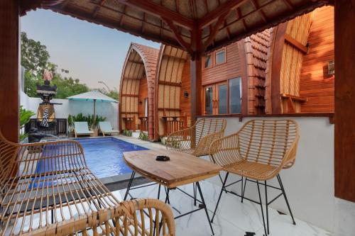 une terrasse avec des chaises, une table et une piscine dans l'établissement Luh Adi Villa 1, Balinese Wooden House in Uluwatu, à Uluwatu