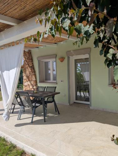 a patio with a table and chairs in front of a house at Domedda Cugnana in Cugnana