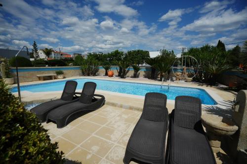 a swimming pool with black reclining chairs next to it at Casa da Veiga de Ponte de Lima in Ponte de Lima