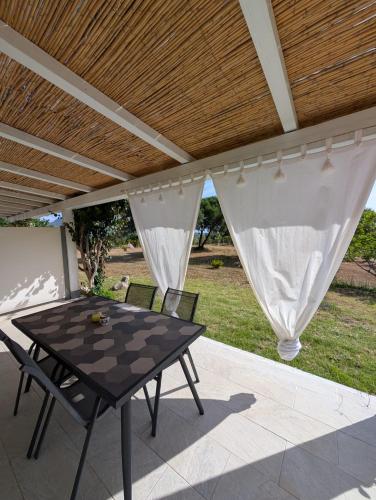 a patio with a table and chairs under a roof at Domedda Cugnana in Cugnana