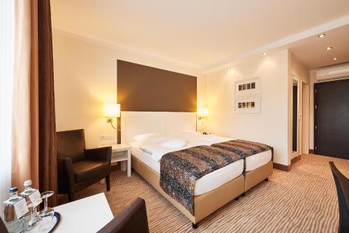 a hotel room with a bed and a chair at MUNTE - Wellnesshotel am Stadtwald in Bremen