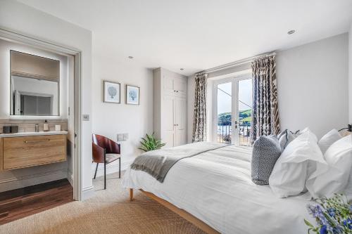 1 dormitorio con cama, lavabo y ventana en Knots Landing, Salcombe, en Salcombe