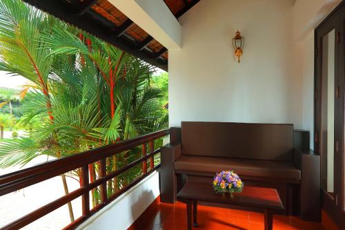 a balcony with a bench and a table and a palm tree at Nihara Resort and Spa Cochin in Cochin