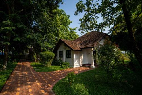 a small white house with a brick driveway at Nihara Resort and Spa Cochin in Cochin