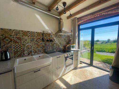 une cuisine avec un évier et une grande fenêtre dans l'établissement Maison Le Garochet, à Digoin