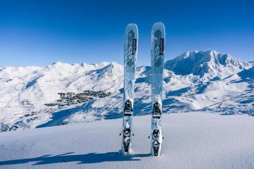 a pair of skis in the snow in front of snow covered mountains at Val Thorens Appartement Cosy centre station in Val Thorens