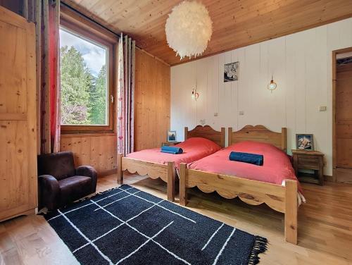 une chambre avec deux lits et une chaise et une fenêtre dans l'établissement Le cosy refuge, à Chamonix-Mont-Blanc