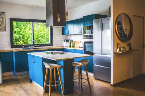 une cuisine avec des placards bleus et un comptoir avec des tabourets dans l'établissement Spacious house with pool in Ondres, à Ondres