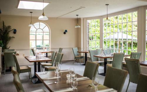 a restaurant with tables and chairs and windows at Flackley Ash Country House Hotel in Rye