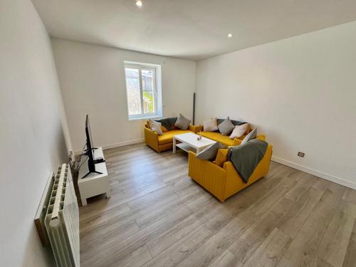 - un salon avec deux canapés jaunes et une télévision dans l'établissement Le Bel'air - T3 pour 5 personnes, à Poitiers