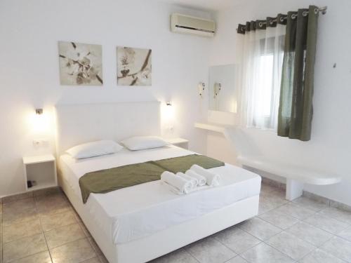a white bedroom with a bed and a bath tub at Anemos Studios in Adamas