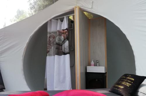 a room with a bed and a shower in a tent at Logements insolites du Domaine de la Tuilière in Carnoules