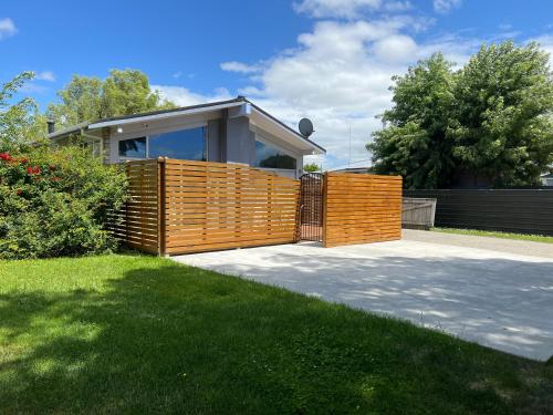 a house with a wooden fence in a yard at Palmy Hideaway - Dog Friendly in Palmerston North