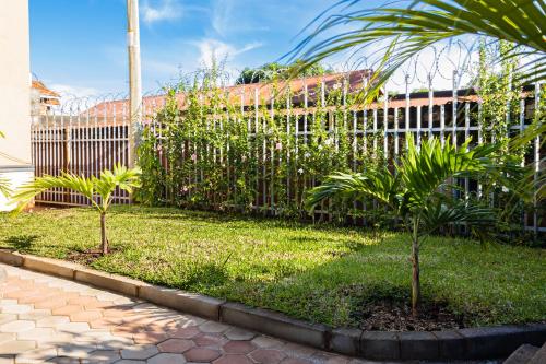 a fence with two palm trees in front of a building at Pitta Opulent Apartments in Kampala