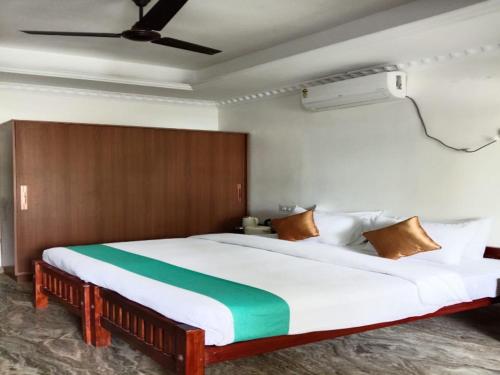 a bedroom with a large bed with a green stripe on it at West Bay MARISOL in Varkala