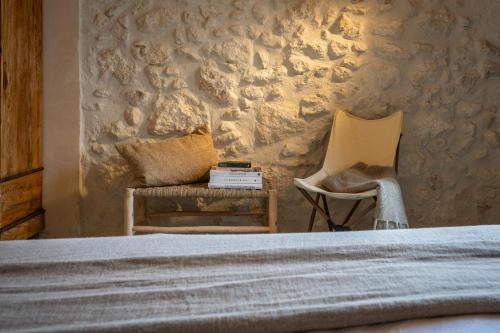 a bedroom with a bed and a chair and a wall at Mas Grimosach - Masía en finca y bodega ecológica - Adults Only in Sant Pau dʼOrdal