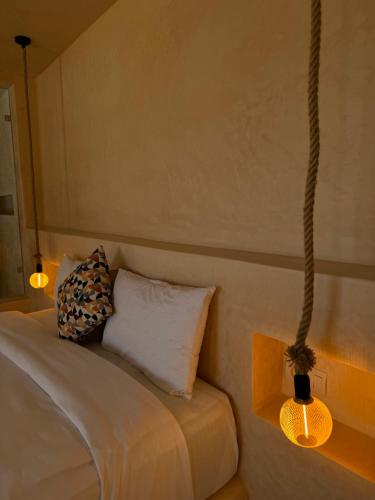 a bed with two pillows and a hanging light at Playa Surf House in Tamraght Ouzdar