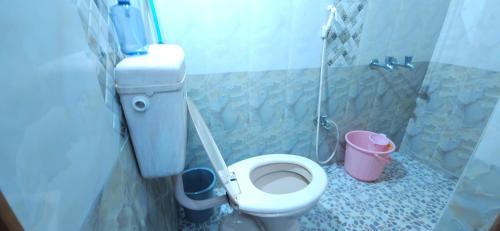 a bathroom with a toilet and a pink bucket at SHI's Kurunji 5BHK Villa in Pollachi in Pollāchi