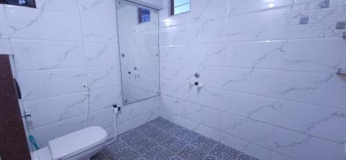 a bathroom with a toilet and white marble walls at SHI's Kurunji 5BHK Villa in Pollachi in Pollāchi