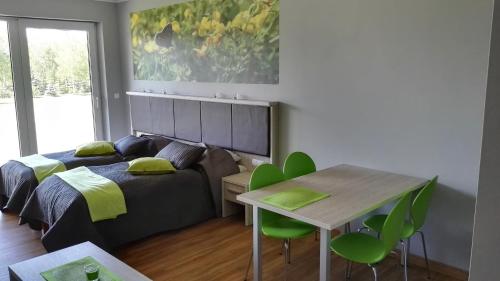 a bedroom with a bed and a table and green chairs at Catalpa Camp Ośrodek Rekreacyjno-Wypoczynkowy nad jeziorem Gopło in Piotrków Kujawski
