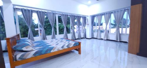 a bedroom with a bed and large windows at SHI's Kurunji 5BHK Villa in Pollachi in Pollāchi