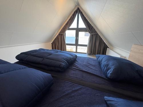 two beds in a room with a large window at Enkhuizer Strand BeachHouse Deck Acht mit Zaun Nr 408 in Enkhuizen