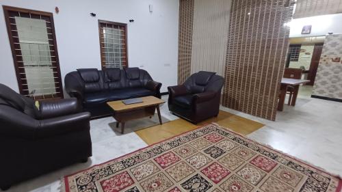 a waiting room with leather chairs and a table at SHI's Kurunji 5BHK Villa in Pollachi in Pollāchi