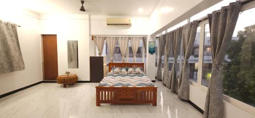 a bedroom with a bed in a room with windows at SHI's Kurunji 5BHK Villa in Pollachi in Pollāchi