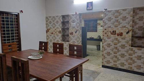 a dining room with a wooden table and a kitchen at SHI's Kurunji 5BHK Villa in Pollachi in Pollāchi