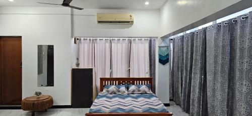 a bedroom with a bed and a window with curtains at SHI's Kurunji 5BHK Villa in Pollachi in Pollāchi