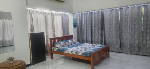 a bedroom with a bed in front of windows at SHI's Kurunji 5BHK Villa in Pollachi in Pollāchi