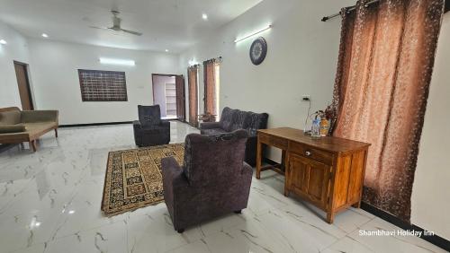 a living room with chairs and a wooden desk at SHI's Kurunji 5BHK Villa in Pollachi in Pollāchi