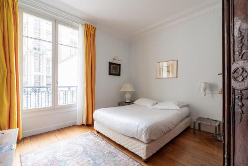 une chambre avec un lit et une grande fenêtre dans l'établissement Veeve - Père-Lachaise Chronicles, à Paris