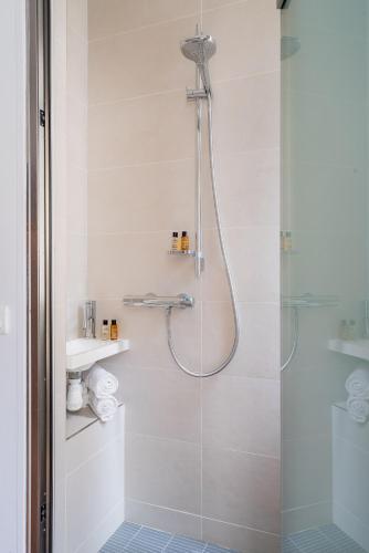 une salle de bain avec une douche avec une porte vitrée dans l'établissement Veeve - Père-Lachaise Chronicles, à Paris
