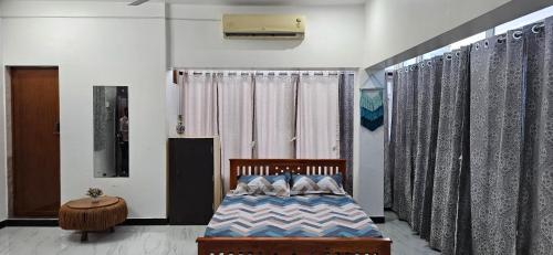 a bedroom with a bed in a room with curtains at SHI's Kurunji 5BHK Villa in Pollachi in Pollāchi