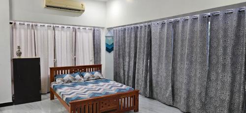 a bedroom with a bed and some curtains at SHI's Kurunji 5BHK Villa in Pollachi in Pollāchi