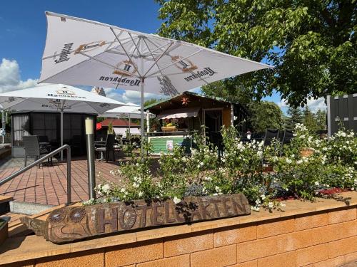 a table with an umbrella and some flowers at Ambiente Hotel Strehla in Strehla