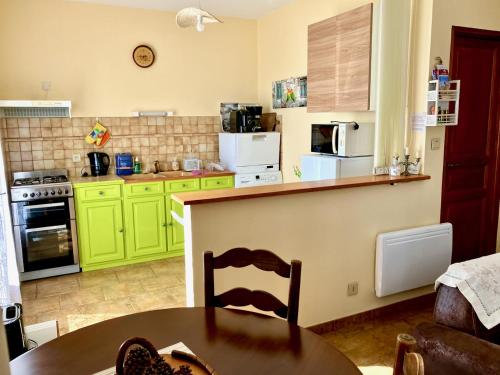 a kitchen with green cabinets and a wooden table at Windmill Cottage of Monpazier in Capdrot