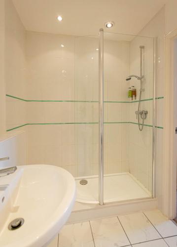 a white bathroom with a shower and a sink at Thomas Paine Hotel in Thetford