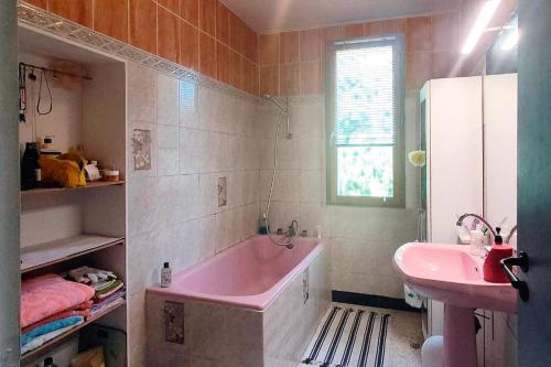 La salle de bains est pourvue d'une baignoire rose et d'un lavabo. dans l'établissement chambre privée dans maison en garrigue, à Nîmes