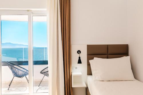 a bedroom with a bed and a balcony with the ocean at Helia Seaside Hotel in Sarandë
