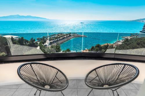 a balcony with two chairs and a view of the ocean at Helia Seaside Hotel in Sarandë