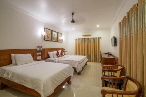 a hotel room with two beds and a chair at Reasey Boutique Villa in Siem Reap