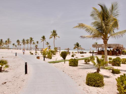 a path on the beach with palm trees and a building at Lux Villa Azure in Salalah