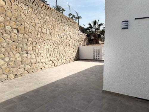 a stone wall next to a white building at Chalet de lujo en Cala Lanuza con vistas al mar in El Campello