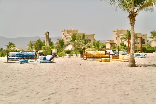 a beach with chairs and palm trees in front of a hotel at Lux Villa Azure in Salalah
