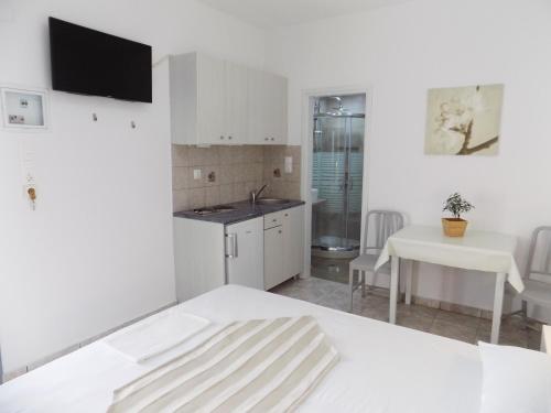 a white kitchen with a white bed and a table at Anemos Studios in Adamas