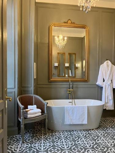 a bathroom with a tub and a mirror and a chair at Chateau Forest in Arette